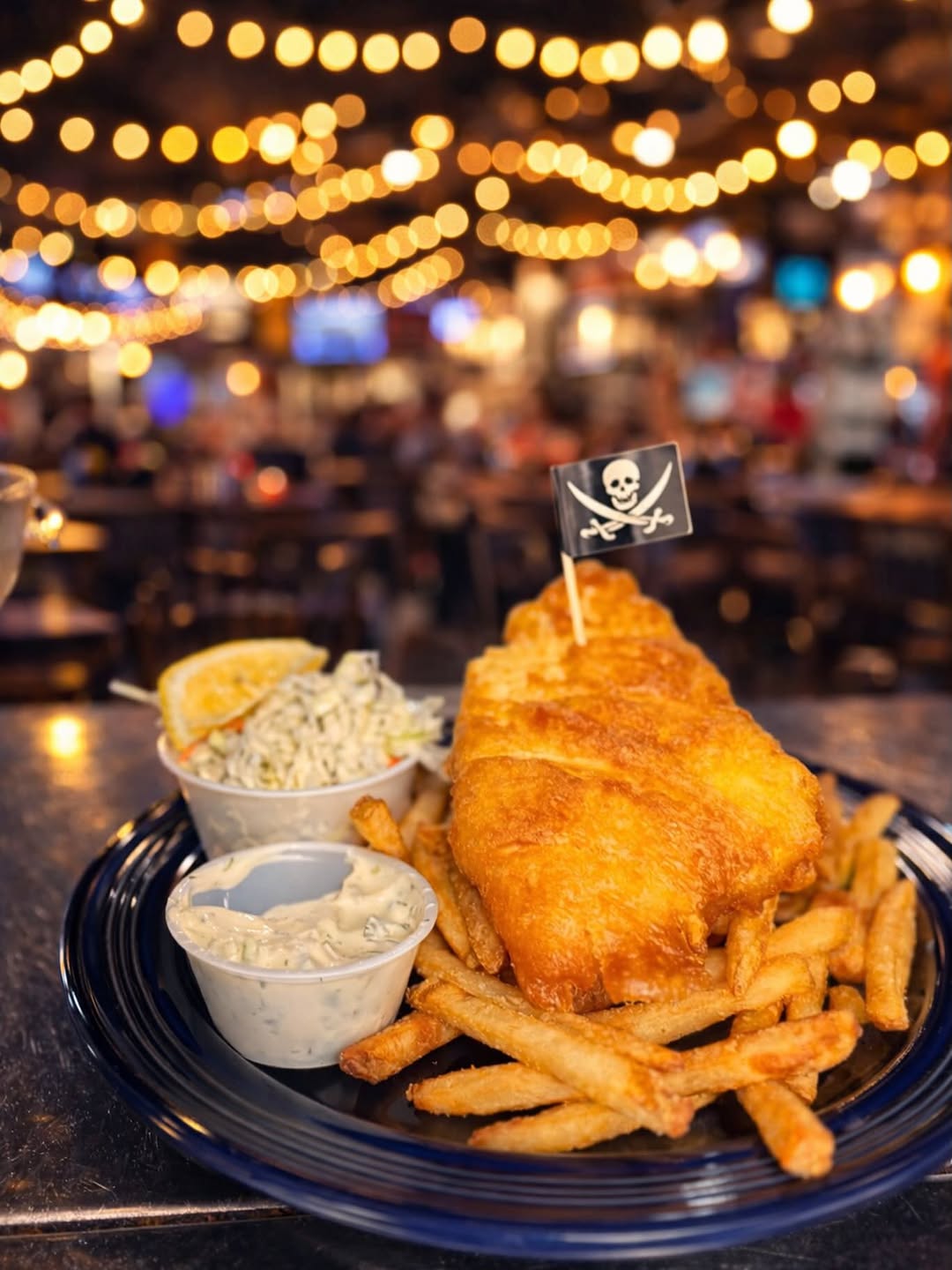 fish and chips in foreground with fairly lights in background